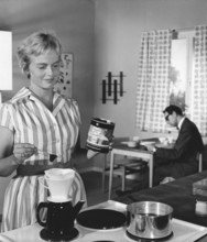 Coffee in the 1960s. A woman is making coffee for her herself and her husband. The way of making