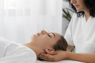 Osteopathist treating female patient by massaging her face