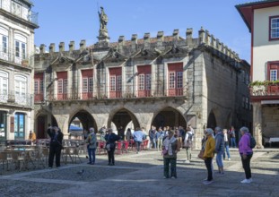 Tourist group viewing historic buildings in Largo da Oliveira square, city of Guimaraes, northern