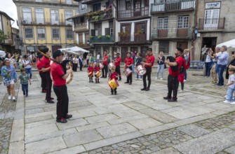 Traditional drum and pipe band perform on city streets on May Day 2025, Guimaraes, Braga district,