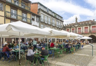 Tables and chairs, historic buildings in Largo da Oliveira square, city of Guimaraes, northern