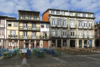 Tables and chairs, historic buildings in Largo da Oliveira square, city of Guimaraes, northern