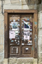 Stickers posters and graffiti tags on old wooden door, Guimaraes, Portugal, Europe