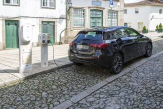 Mercedes-Benz hatchback car being recharged with electricity in city centre street, Guimaraes,