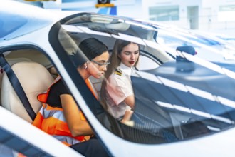 Two female pilots, one in uniform and the other in a safety vest, collaborate inside an aircraft