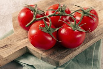 Fresh red tomatoes on a branch, on a wooden chopping board, close-up, no people