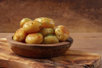 Baked new potatoes, with butter and dill, on a wooden plate, homely, rustic, no people