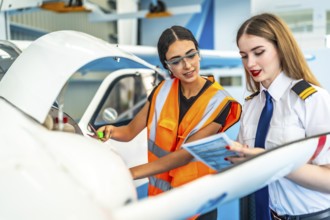 Aircraft maintenance engineer and a pilot are performing a pre flight check, consulting a