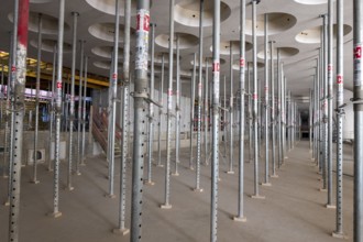 Rows of scaffolding in an unfinished interior with perforated ceiling, supports, construction site