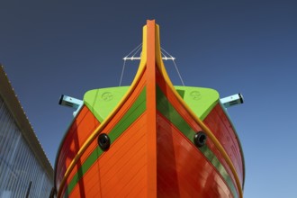Close-up of the bow of a large orange boat in front of a clear sky, Diakofti boatyard, new
