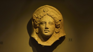 Ancient stone head of a goddess, exhibited in a museum-like setting, found in the cave of Aspri