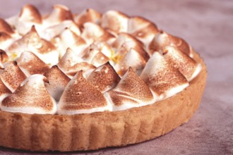 Lemon meringue cake, golden brown, toasted, on a light table, no people