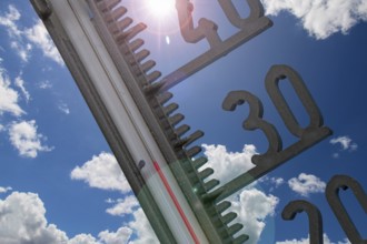 (Photomontage) Symbolic image of heat: thermometer in front of a summer sky
