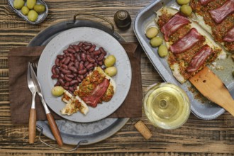 A delectable plate of fish topped with herbs and meat is presented alongside kidney beans and green