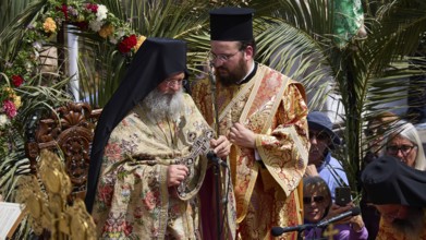 Two priests in rich robes stand in the middle of a solemn ceremony with religious symbols and
