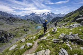 Mountaineer on hiking trail in mountain landscape, descent at Col du Louvie, view of mountain lake
