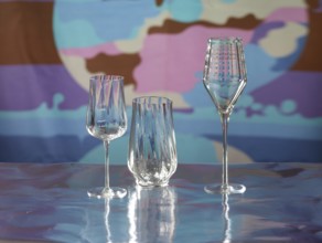 Various glasses on silver foil, behind them various colour elements, studio shot
