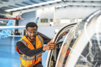 Aircraft maintenance engineer wearing safety glasses and a high visibility vest, performing a pre