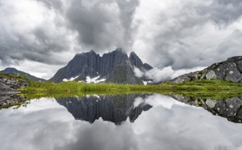 Small lake in mountain landscape, hike to Mount Barden, reflection with mountain peak Breidtind,