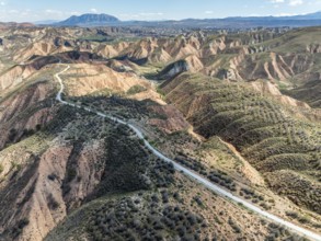Winding road on a plateau, surrounded by colorful canyons and gorges, aerial view, Gorafe Desert,