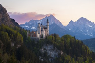 Neuschwanstein Castle after sunset with mountain landscape in the background, Schwangau near