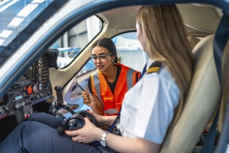 Aircraft maintenance engineer is explaining something to a pilot sitting in the cockpit of a small