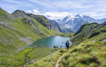 Mountaineer on hiking trail in picturesque mountain landscape, view of mountain lake Lac du Louvie