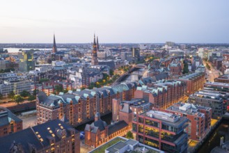 Aerial view of the Speicherstadt Hamburg at blue hour with churches and Alster in the background,
