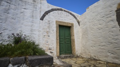 Green door in a courtyard with plants and whitewashed walls, Monastery of the Revelation, Moni tis