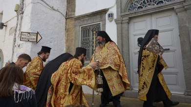 Priests in gold and black robes enter a door during a procession, Orthodox ceremony, monks of St