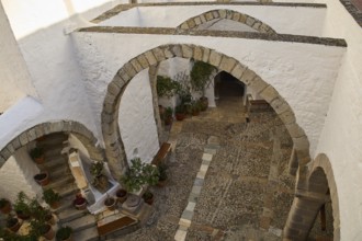White courtyard with stone arches and plants in traditional style, Monastery of St John the