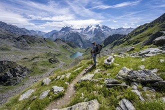 Mountaineer on hiking trail in mountain landscape, descent at Col du Louvie, view of mountain lake