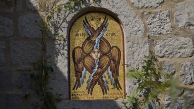 Detailed view of a mosaic with a winged saint on a stone wall, woman's monastery, Evangelismou