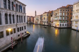 View of the Grand Canal with gondoliers at sunset, picturesque evening mood with illuminated