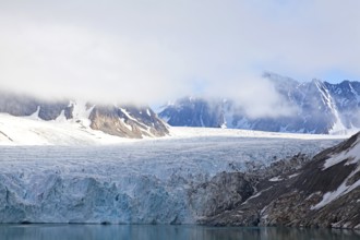 A fascinating glacier with snow-covered mountains and clouds creating a calm and peaceful