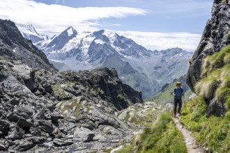 Mountaineer on hiking trail in mountain landscape, descent at Col du Louvie, view of the summit of