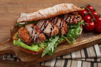 Sandwich with duck breast and arugula, balsamic sauce, on a wooden chopping board, breakfast,