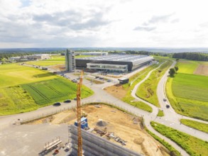Industrial plant in sunshine with surrounding fields and a construction crane, ING Park development