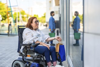 Smiling woman in a wheelchair holding shopping bags enjoying a day of shopping in a modern city