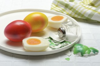 Easter eggs and salt shaker on plate, partially peeled