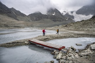 Mountaineers at a makeshift bridge over a stream, glacier river at the Glacier de Cheilon, in the