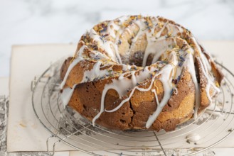 Marble bundt cake, cake with icing and edible flowers on a cake rack, light background