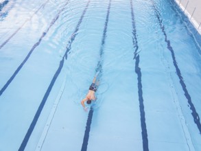 A person swims along the lanes in a large, blue swimming pool, outdoor pool Calw, Black Forest,