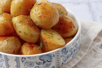 Baked new potatoes, with butter and dill, on a white plate, at home, no people