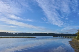 A long jetty on the shore of a calm lake under an overcast sky, Lake Mahinapua, Ruatapu, South