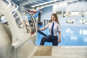 Confident female pilot boarding a small aircraft in a hangar, readying for an exciting flight and