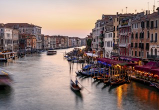 View of the Grand Canal with gondoliers at sunset, picturesque evening mood with illuminated