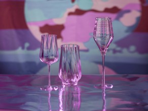 Various glasses on silver foil, behind them various colour elements, studio shot