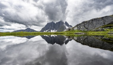 Small lake in mountain landscape, hike to Mount Barden, reflection with mountain peak Breidtind,