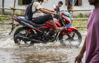 Commuters passing through a waterlogged street following heavy rainfall in Guwahati, India, on 1